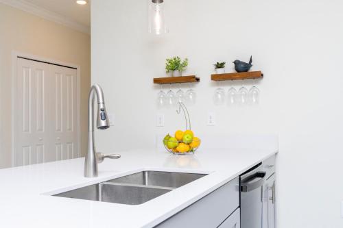 eine weiße Küche mit einem Waschbecken und einer Schale Obst in der Unterkunft Stunning 5 Bd w/ Pool Close to Disney 2905 in Kissimmee