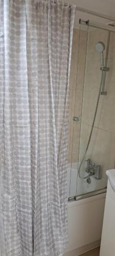 ein Bad mit einer Dusche und einem weißen Duschvorhang in der Unterkunft Upper Tooting Road in London