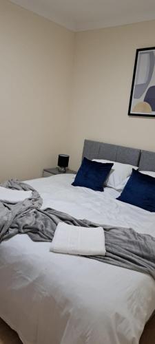 ein großes weißes Bett mit blauen Kissen darauf in der Unterkunft Upper Tooting Road in London