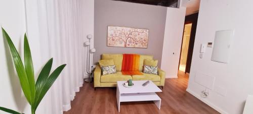 een woonkamer met een gele bank en een tafel bij Apartamento Viña P. Málaga Centro in Málaga