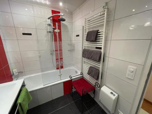 La salle de bains est pourvue d'une baignoire et d'une chaise rouge. dans l'établissement Appartement Holiday, à Maishofen