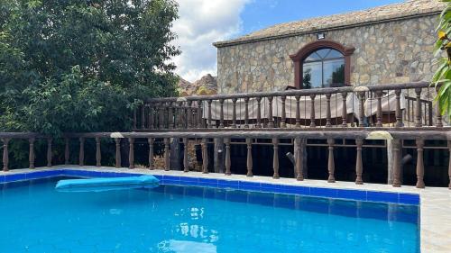 a swimming pool next to a wooden fence at Sunrise Farm استراحة مطلع الشمس in Hatta