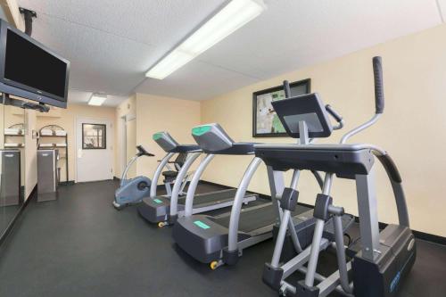 a gym with several tread machines and a flat screen tv at Ramada by Wyndham Rochelle Park Near Paramus in Rochelle Park