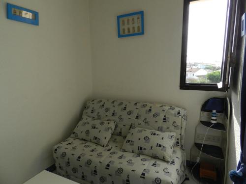 - un canapé dans un coin d'une chambre avec fenêtre dans l'établissement Charmant studio avec piscine à La Rochelle, proche port des Minimes, commerces et bus - FR-1-551-30, à La Rochelle