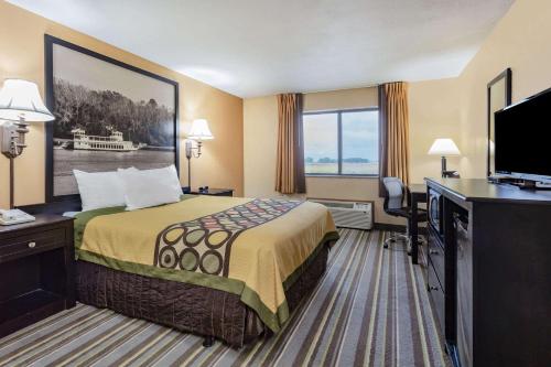 a hotel room with a bed and a flat screen tv at Super 8 by Wyndham Iowa Falls in Iowa Falls