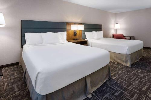 a hotel room with two beds and a chair at Wingate by Wyndham Vineland in Vineland