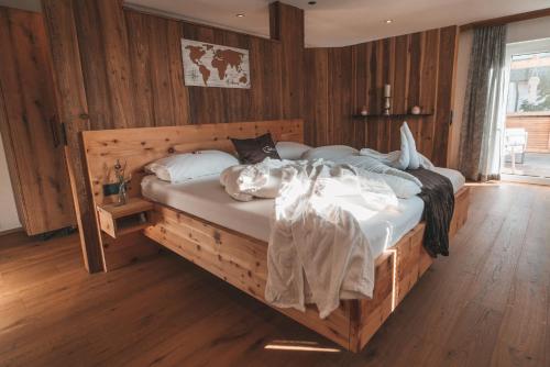 Schlafzimmer mit einem Holzbett mit weißer Bettwäsche in der Unterkunft Landgasthof Wöhrer in Aigen im Ennstal