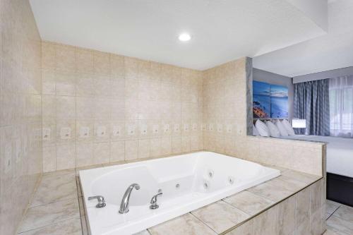 eine große Badewanne im Bad mit Fenster in der Unterkunft Days Inn by Wyndham N Orlando/Casselberry in Orlando