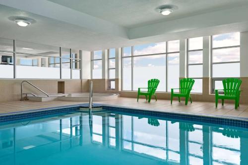 a swimming pool with two green chairs and a tub at Wyndham Garden Niagara Falls Fallsview in Niagara Falls