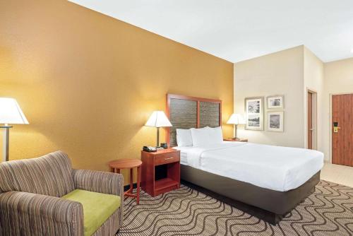 a hotel room with a bed and a chair at La Quinta by Wyndham Midwest City - Tinker AFB in Midwest City