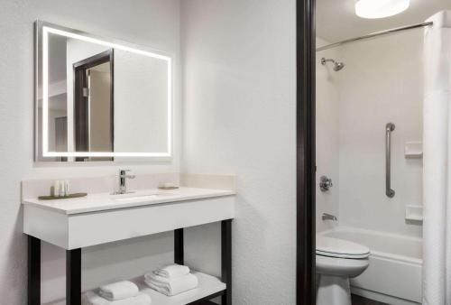 a bathroom with a sink and a toilet and a mirror at La Quinta by Wyndham Cleveland Airport West in North Olmsted