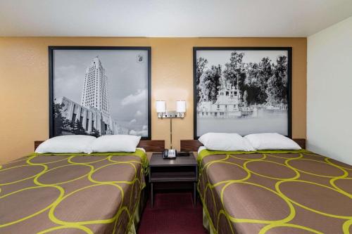 two beds in a hotel room with posters on the wall at Super 8 by Wyndham Kinder/Coushatta near Casino in Kinder