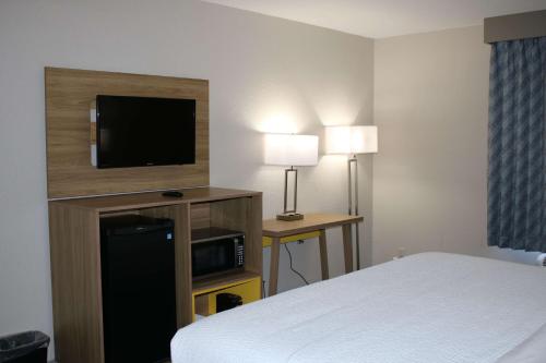 a hotel room with a bed and a flat screen tv at Days Inn by Wyndham Waco University Area in Waco