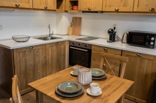 een keuken met een houten tafel met borden erop bij Pirin Golf and Spa Cozy Studio in Bansko