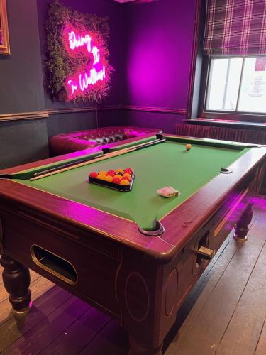 uma mesa de bilhar num quarto com iluminação rosa em The Wellington Pub Cromer em Cromer
