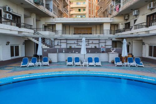a large swimming pool with chairs and umbrellas at AIFU Hotel El Montazah Alexandria in Alexandria