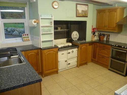 a large kitchen with wooden cabinets and white appliances at Abbeybank Lodge in New Abbey