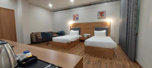 Habitación de hotel con 2 camas y escritorio en Hotel BMD The Grand en Bhīlwāra