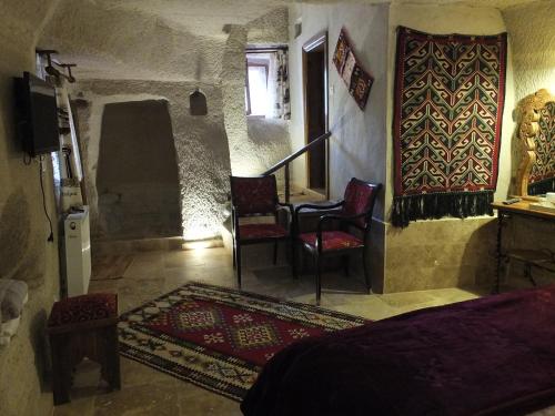 a bedroom with a bed and two chairs and a television at Anatolia cave hotel Pension in Goreme