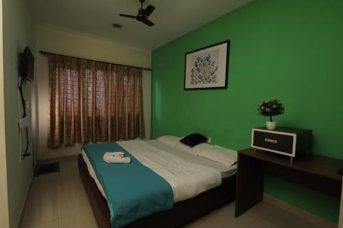 1 dormitorio con paredes verdes y 1 cama con escritorio en Nilgiris Inn By Lexstays Kotagiri, Ooty en Kotagiri