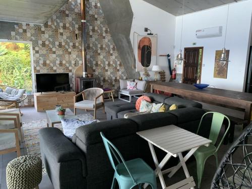 a living room with a couch and chairs and a tv at Sunrise House Azores - jacuzzi in Senhora da Nazaré