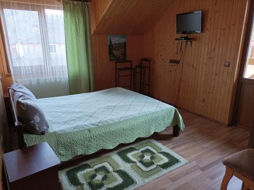 1 dormitorio con 1 cama y TV en una habitación en Сімейний котедж У Діани en Tatariv