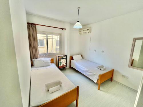 ein kleines Zimmer mit 2 Betten und einem Spiegel in der Unterkunft Two Bedroom City Seaside Apartment in Limassol