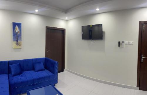 a room with a blue couch and a tv on a wall at Premier Heights Jhelum in Jhelum