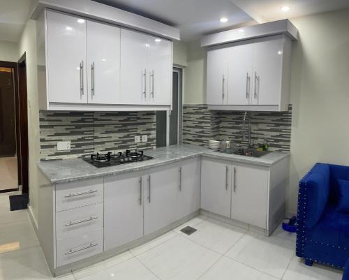 a kitchen with white cabinets and a blue chair at Premier Heights in Jhelum