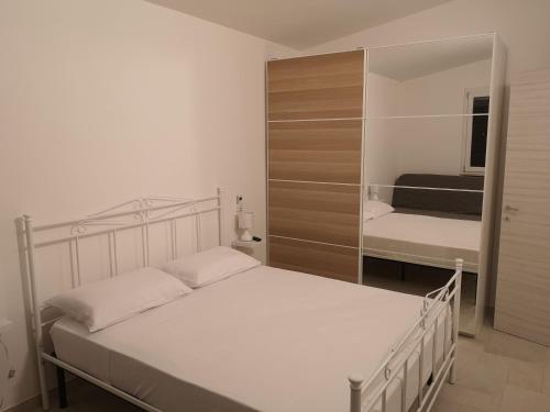 a bedroom with a white bed and a mirror at Casa Vacanze Granieri in Leporano Marina