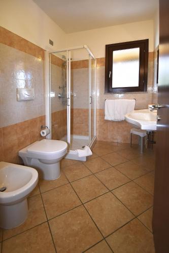 a bathroom with two sinks and a toilet and a shower at Hotel Il Girasole in Villasimius