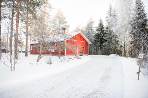 a red barn in the snow next to a road at Lepikko - Helppoa majoitusta, Easy accommodation in Alajärvi