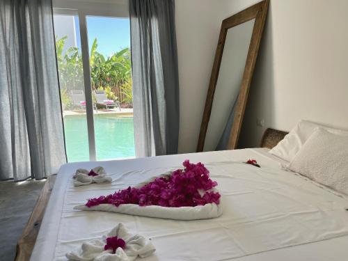 łóżko z fioletowymi kwiatami w obiekcie Tangawizi Villa with Private Pool ZanzibarHouses w mieście Kiwengwa