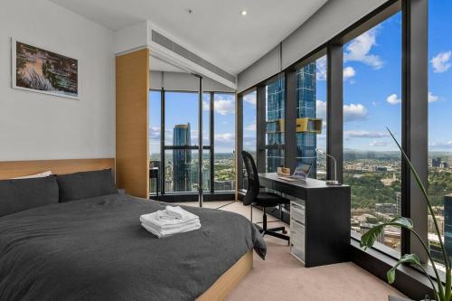 a bedroom with a bed and a desk and windows at Southbank CBD Apartment with Spectacular Views in Melbourne