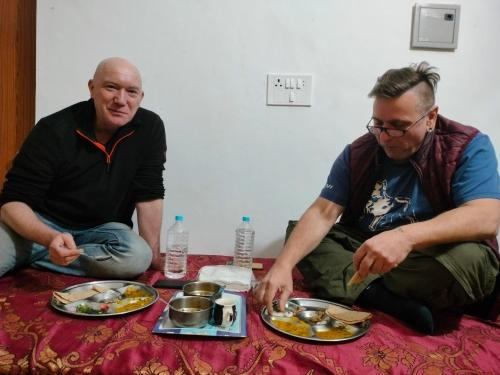 Hello India home stay في خاجوراهو: اثنين من الرجال جالسين على الأرض مع أطباق من الطعام