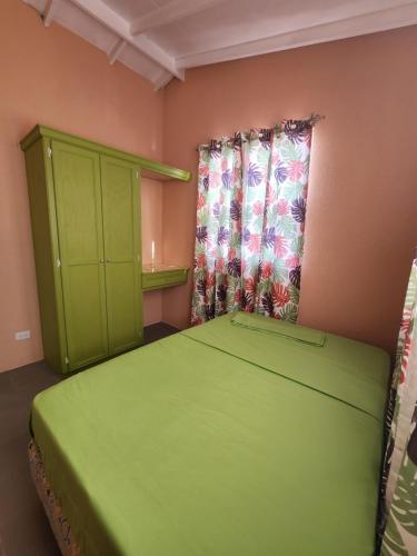 Un dormitorio con una cama verde y una ventana en El Palacio Hidden City Place #2, en Bridgetown
