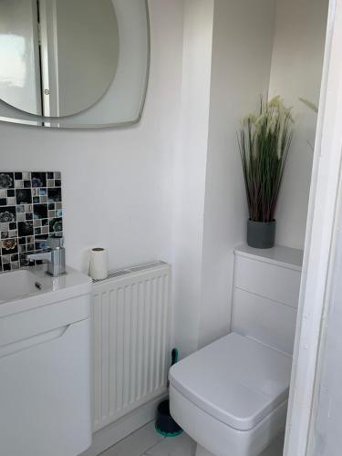 a white bathroom with a toilet and a mirror at Newly renovated 2-Bed House in Gorleston-on-Sea in Great Yarmouth