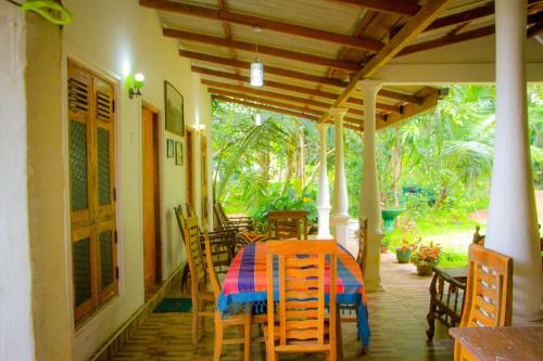 a dining room with a table and chairs on a porch at Travelodge Sigiriya in Sigiriya