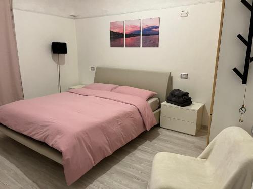 een slaapkamer met een roze bed en een stoel bij Casa vacanza Pratola in Pratola Peligna