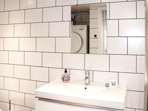 Baño de azulejos blancos con lavabo y espejo en Holiday home MUNKA-LJUNGBY VI, en Munka-Ljungby