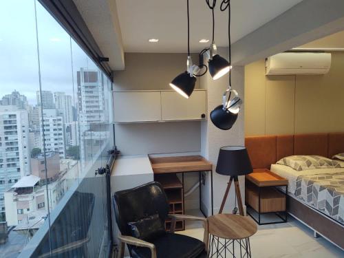 1 dormitorio con balcón, cama y escritorio en apartamento 5 estrelas bela vista, en São Paulo