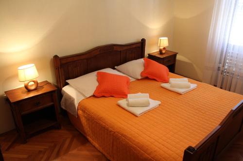 a bedroom with a bed with two towels and two lamps at Apartments Stari Šibenik in Grebaštica