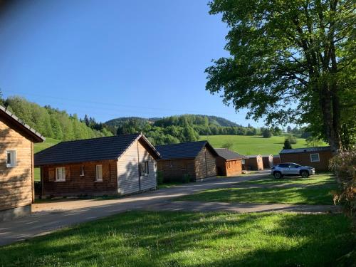 een rij cottages met een auto op een weg bij Camping Le Miroir in Les Hôpitaux-Neufs