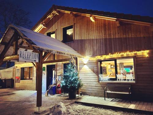 a building with a christmas tree in front of it at Camping Le Miroir in Les Hôpitaux-Neufs