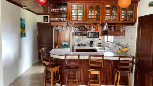 a kitchen with wooden cabinets and a island with chairs at Las Pavitas Cottages in Fortuna