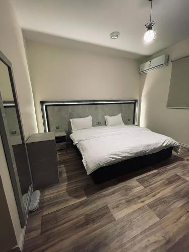 Schlafzimmer mit einem Bett mit weißer Bettwäsche und Holzböden in der Unterkunft sky hotel in Al-'Ula