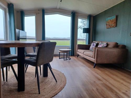 uma sala de estar com uma mesa e um sofá em Chalet duunzicht Texel em De Cocksdorp