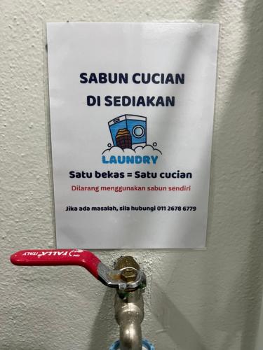 a sign on a wall above a sink with a wrench at Ali Homestay Sungai Petani in Sungai Petani