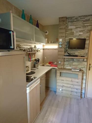 Il comprend une cuisine avec des comptoirs blancs et une télévision murale. dans l'établissement Le Diamant 1 App R 12, à Les Deux Alpes