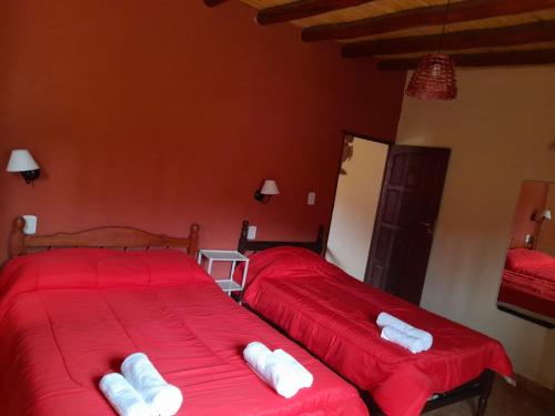 La Herencia Tilcara في تيلكارا: سريرين في غرفة ذات أغطية حمراء ووسائد بيضاء